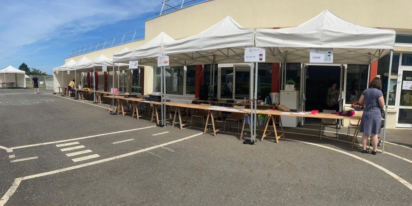 Les stands blancs de la kermesse alignés dans la cour de l'école